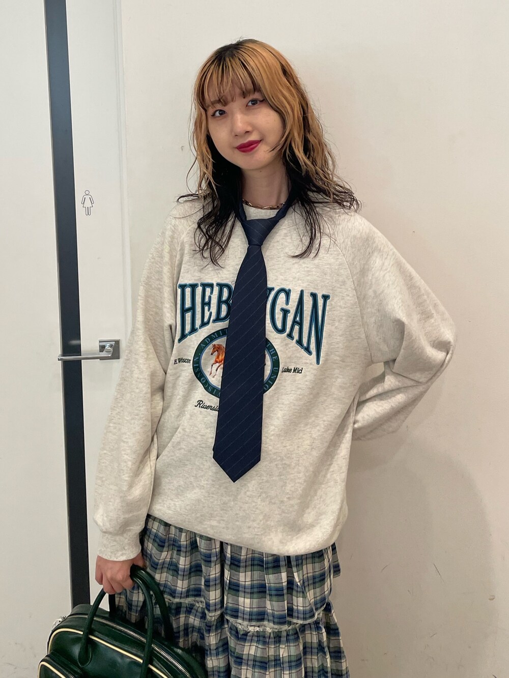 グレー系のスウェット、グリーン系のスカート、グリーン系のボストンバッグを着用したレディースの夏コーディネートの4枚目の写真