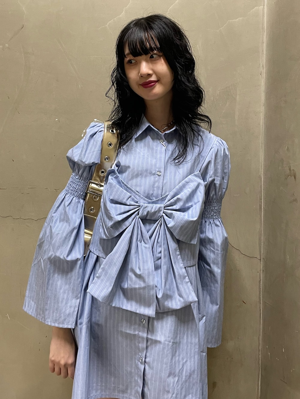 ブルー系のシャツワンピース、ゴールド系のハンドバッグ、ブラック系のブーツを着用したレディースの夏コーディネートの5枚目の写真