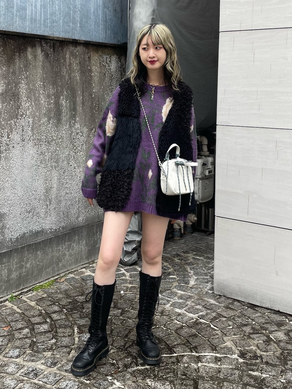 パープル系のニット/セーター、ホワイト系のショルダーバッグ、ブラック系のベストを着用したレディースの冬コーディネートの2枚目の写真