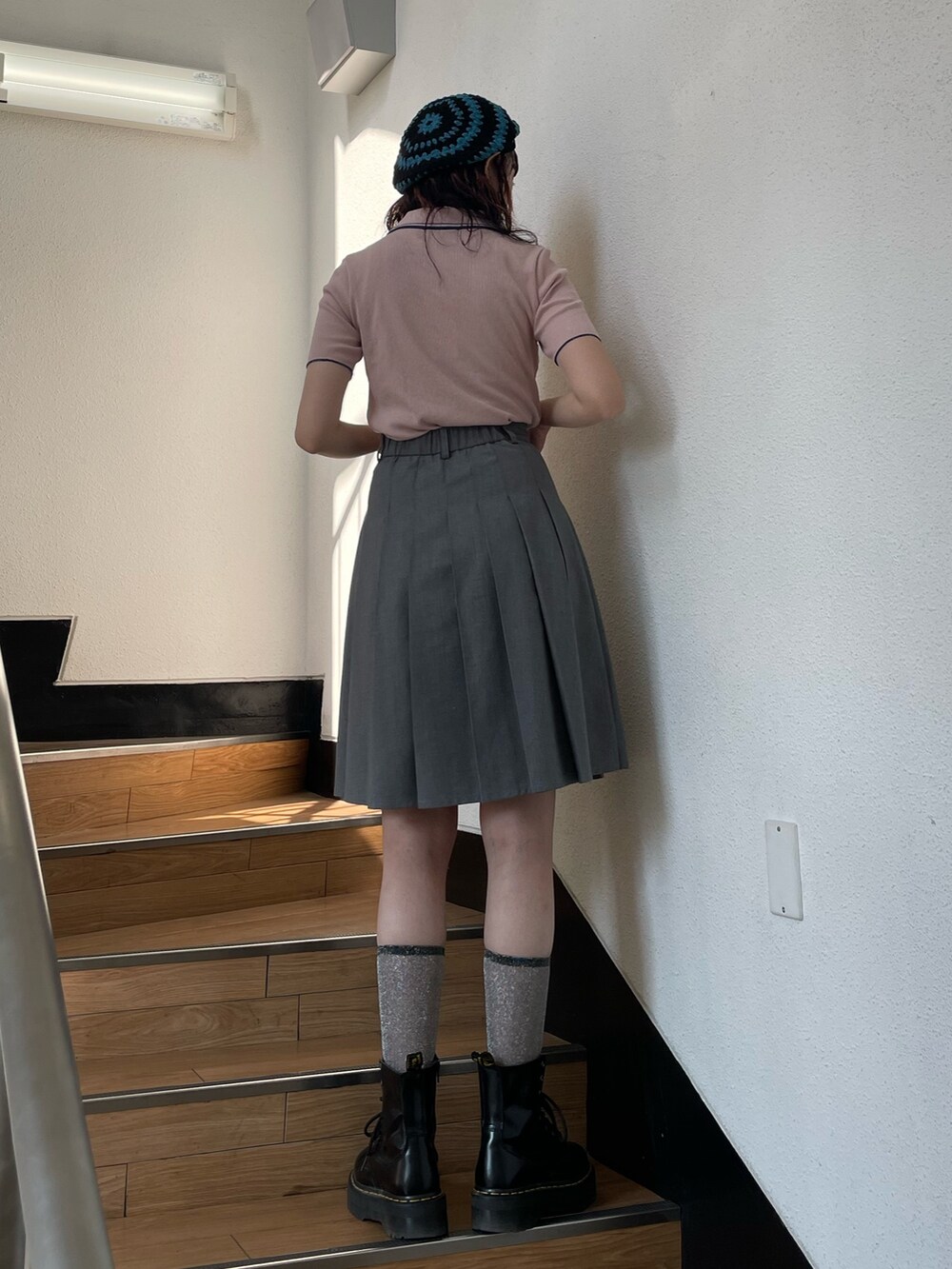 グレー系のスカート、ピンク系のポロシャツ、ブラック系のその他シューズを着用したレディースの春コーディネートの3枚目の写真