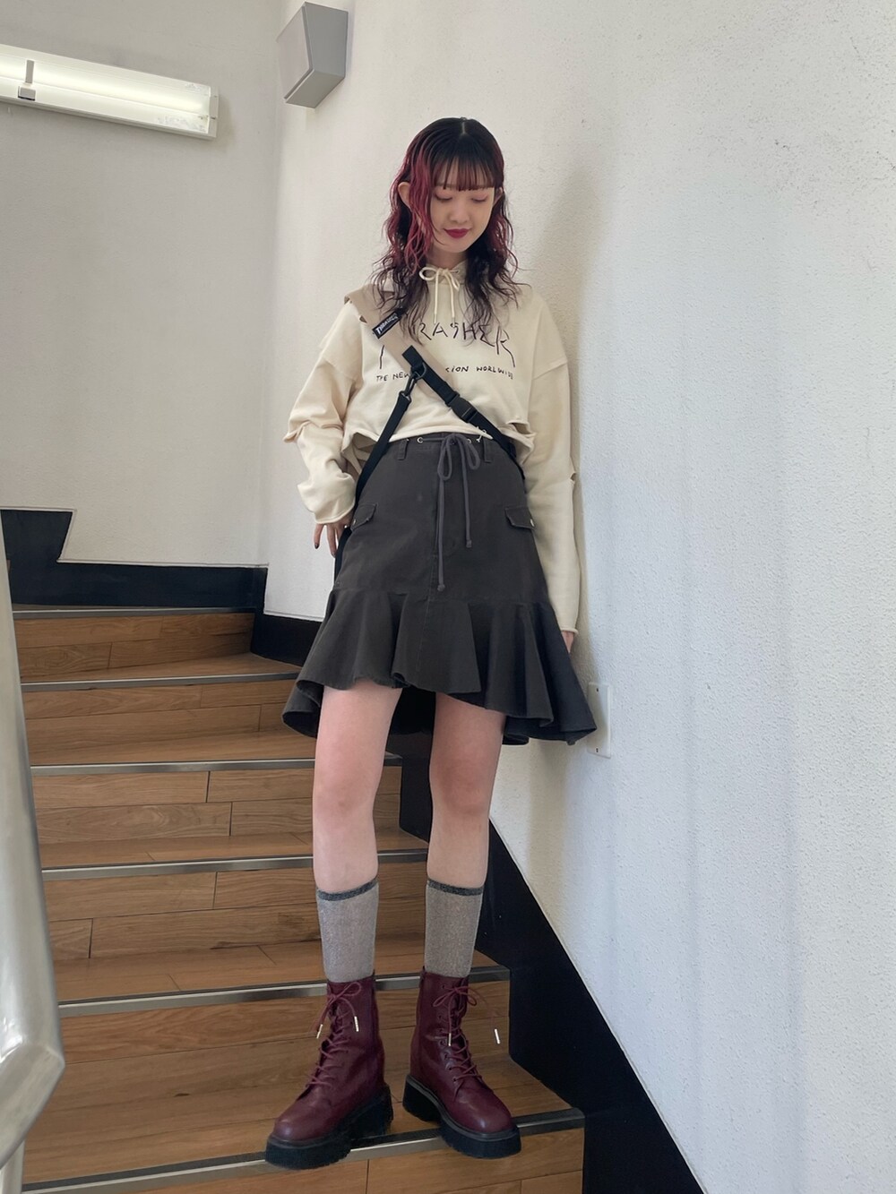 ホワイト系のパーカー、レッド系のブーツ、ブラック系のスカートを着用したレディースの春コーディネートの2枚目の写真