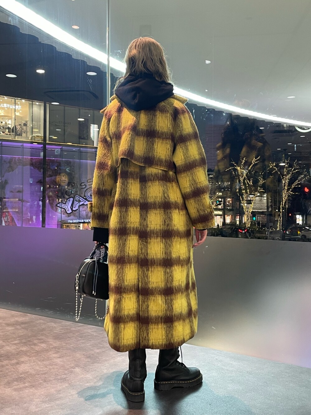 イエロー系のチェスターコート、ブラック系のパーカー、ブラック系のショルダーバッグを着用したレディースの冬コーディネートの3枚目の写真