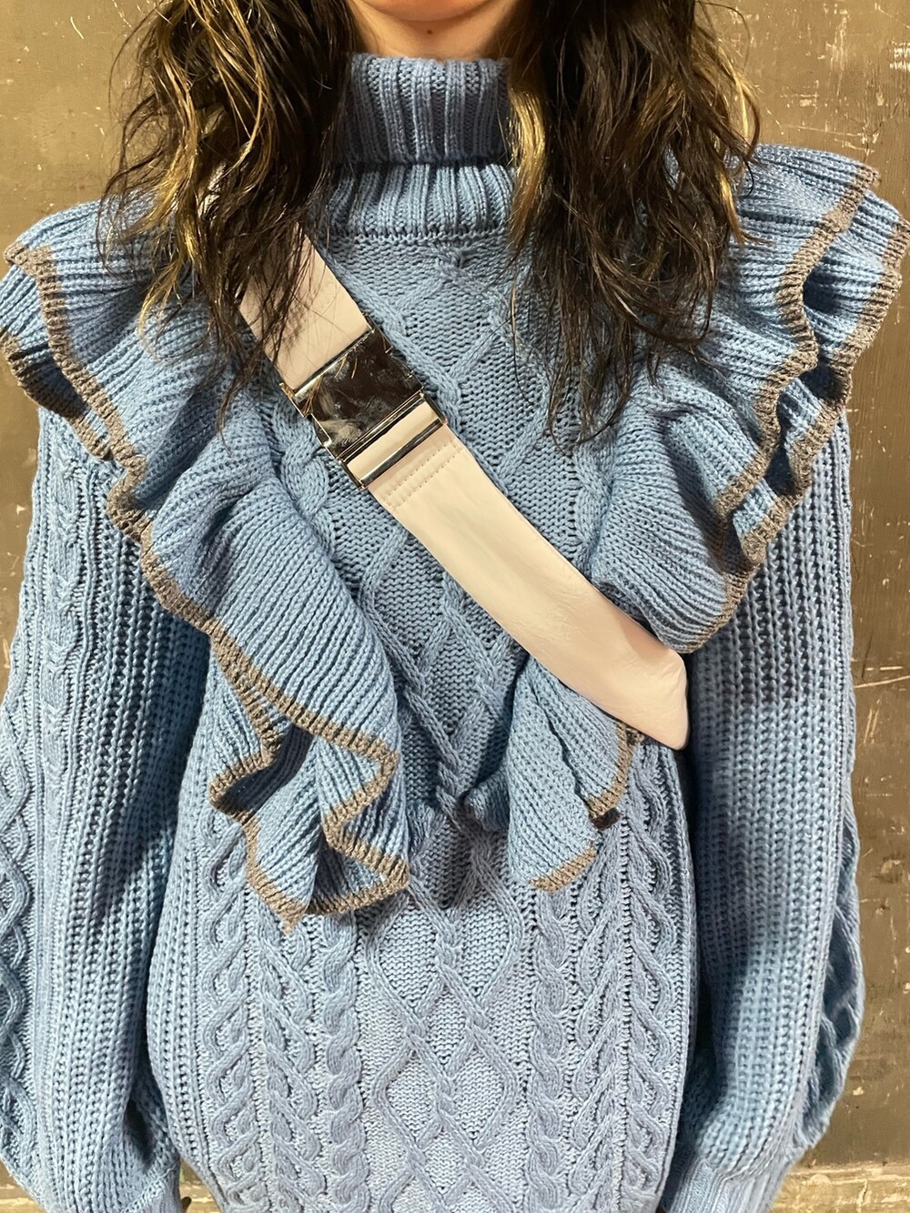 ブラック系のブーツ、ホワイト系のハンドバッグ、ブルー系のニット/セーターを着用したレディースの冬コーディネートの6枚目の写真