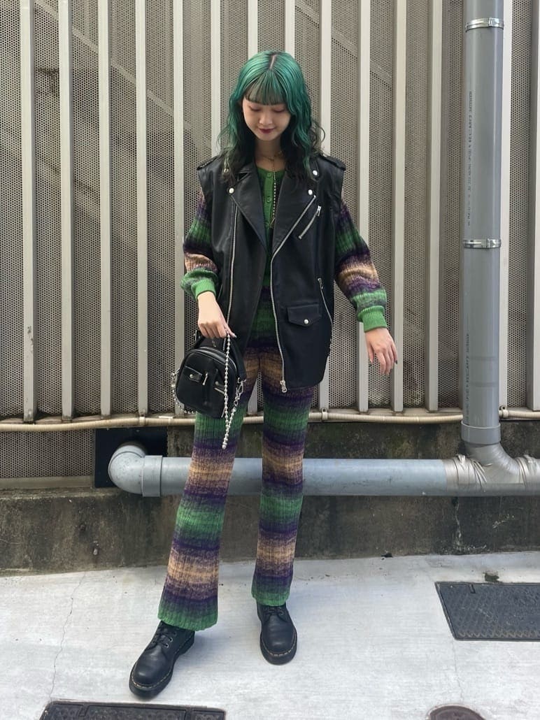 ブラック系のライダースジャケット、グリーン系のその他パンツ、ブラック系のハンドバッグを着用したレディースの秋コーディネートの2枚目の写真