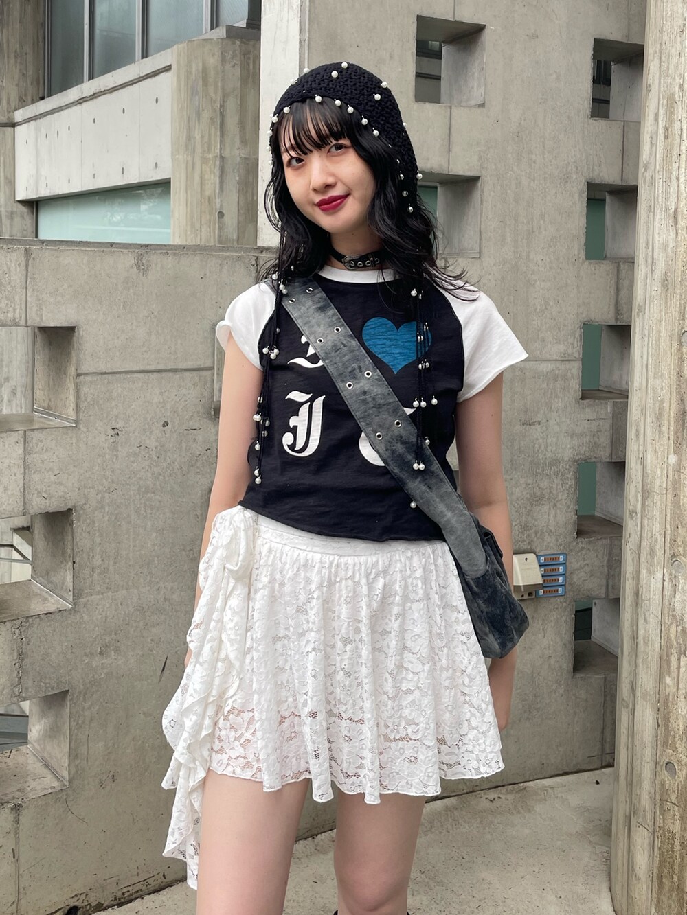 ブラック系のTシャツ/カットソー、ブラック系のメッセンジャーバッグ、ホワイト系のスカートを着用したレディースの春コーディネートの3枚目の写真