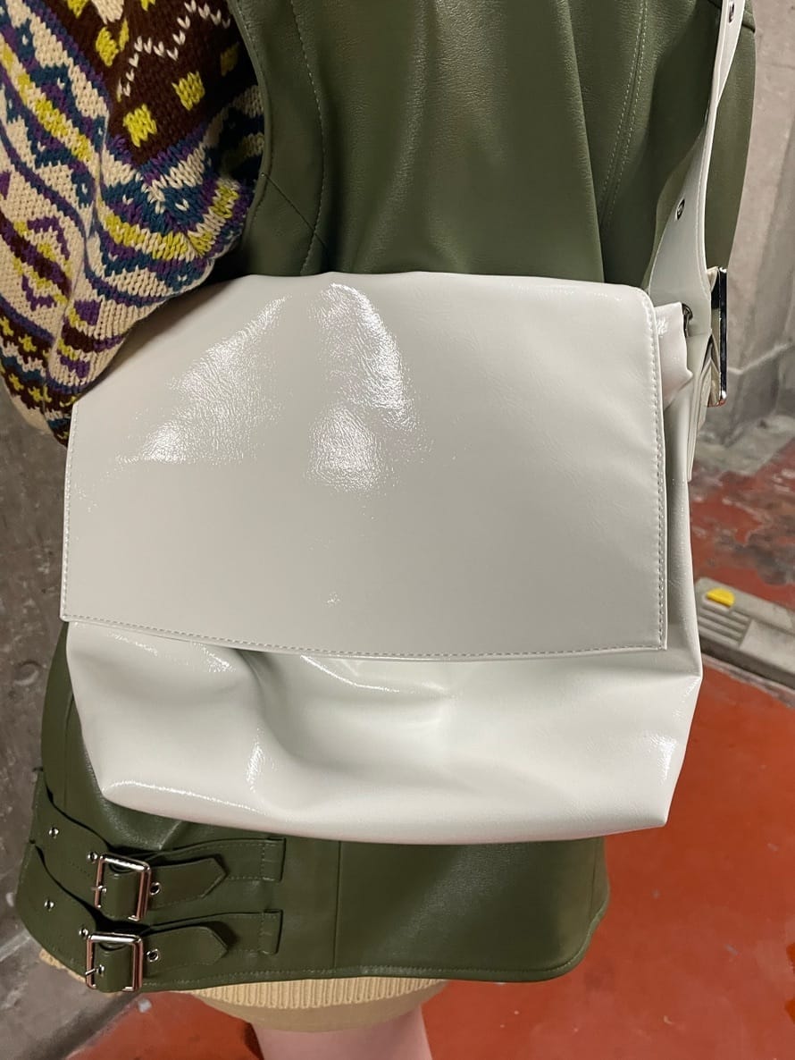 ブラック系のブーツ、ホワイト系のハンドバッグ、グリーン系のライダースジャケットを着用したレディースの秋コーディネートの8枚目の写真