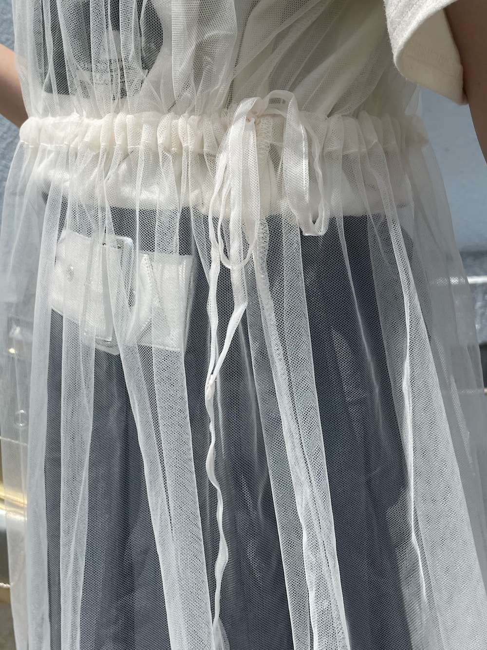 ホワイト系のワンピース、グレー系のスカート、ゴールド系のハンドバッグを着用したレディースの夏コーディネートの8枚目の写真