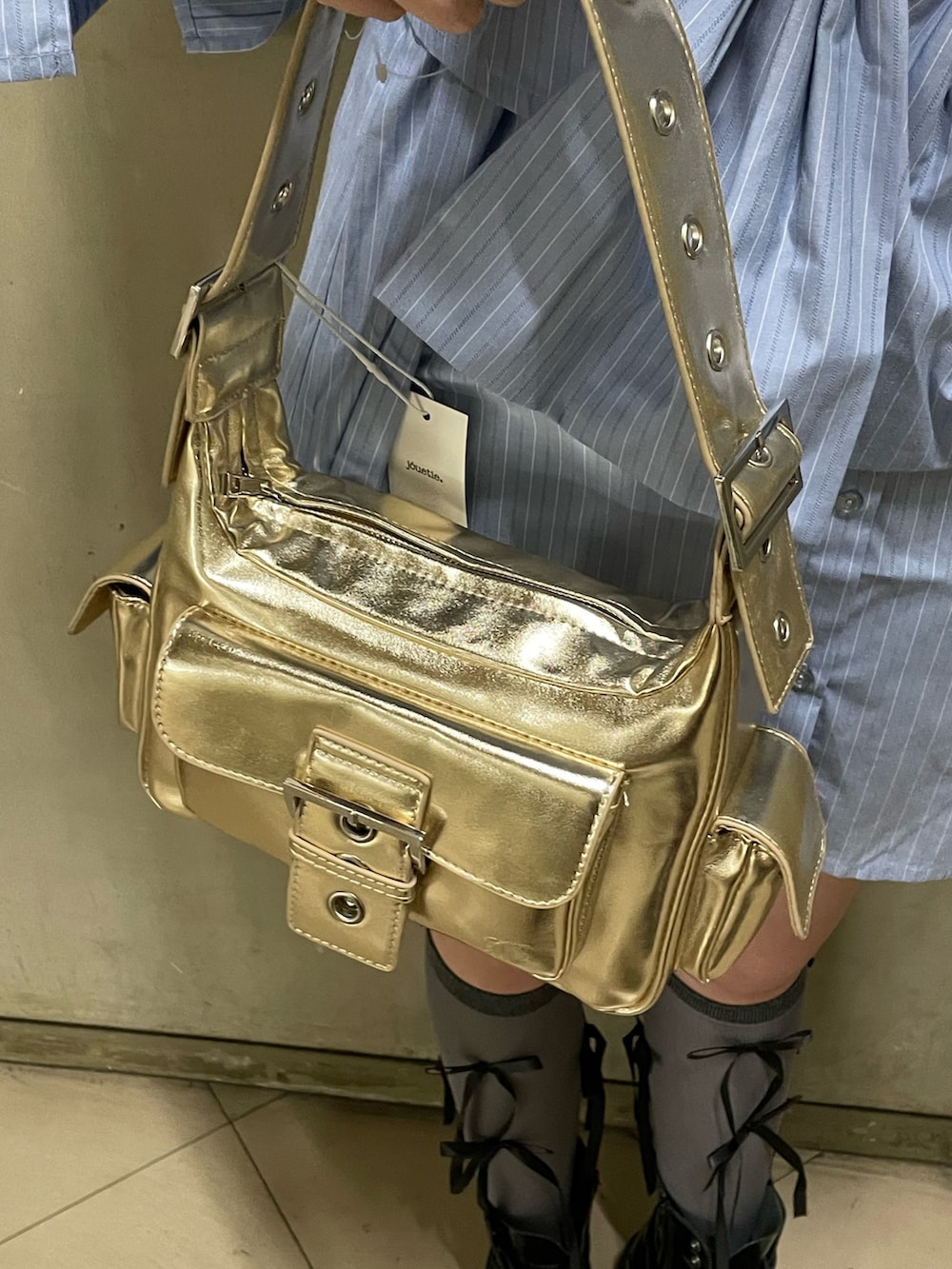 ブルー系のシャツワンピース、ゴールド系のハンドバッグ、ブラック系のブーツを着用したレディースの夏コーディネートの9枚目の写真