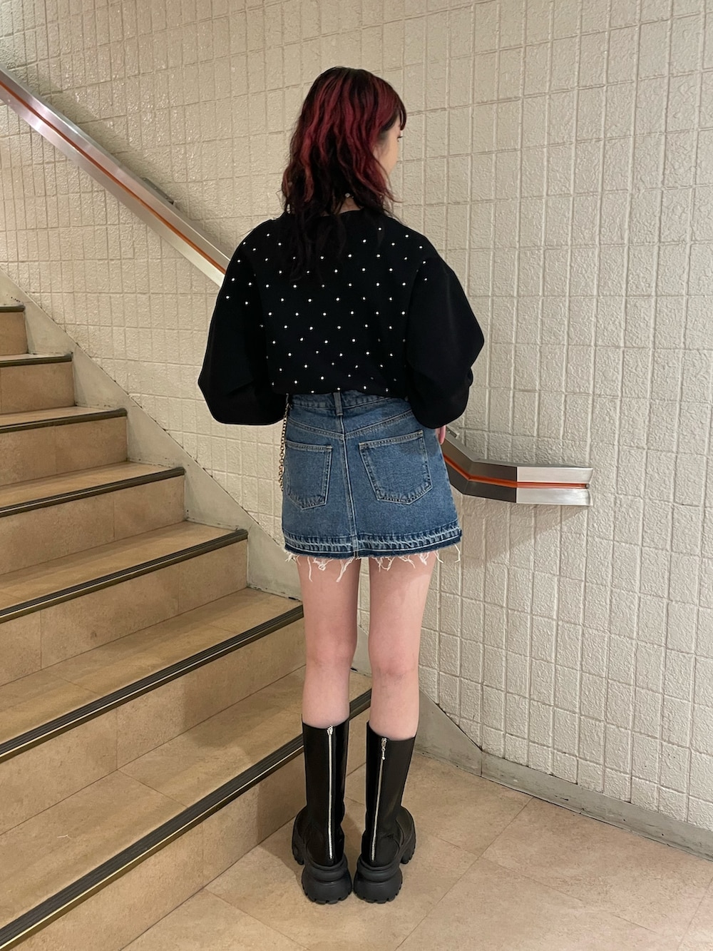 ブラック系のスウェット、ブルー系のデニムパンツ、ブラック系のブーツを着用したレディースの冬コーディネートの3枚目の写真