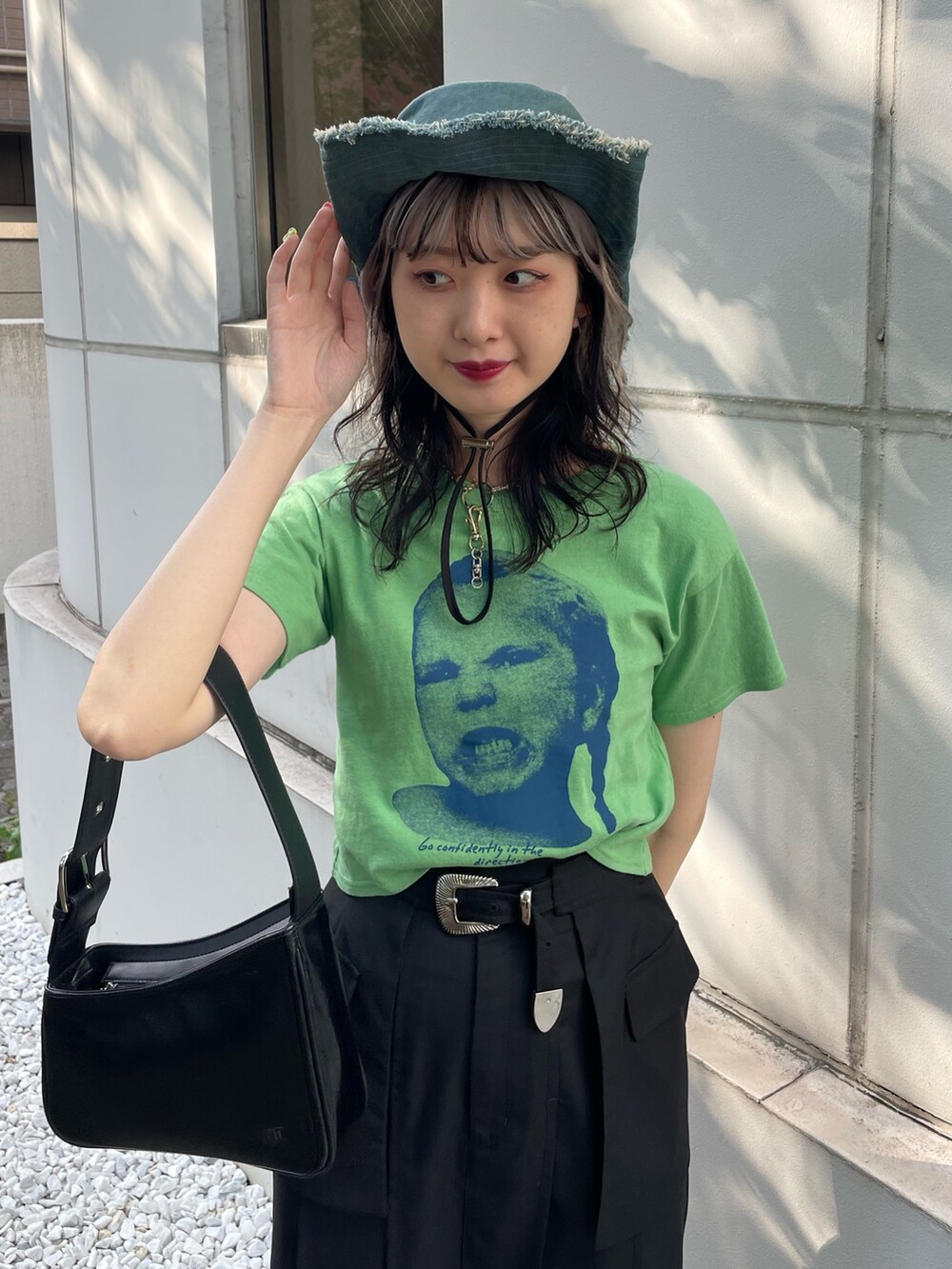 グリーン系のTシャツ/カットソー、ブラック系のスカート、ブラック系のブーツを着用したレディースの春コーディネートの4枚目の写真