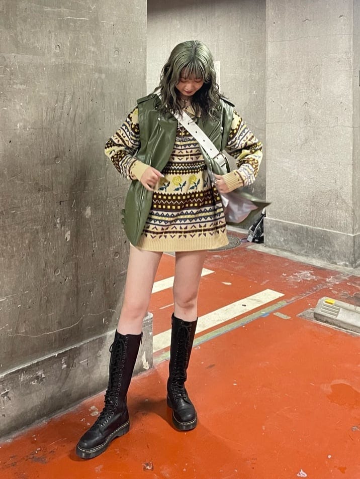 ブラック系のブーツ、ホワイト系のハンドバッグ、グリーン系のライダースジャケットを着用したレディースの秋コーディネートの2枚目の写真