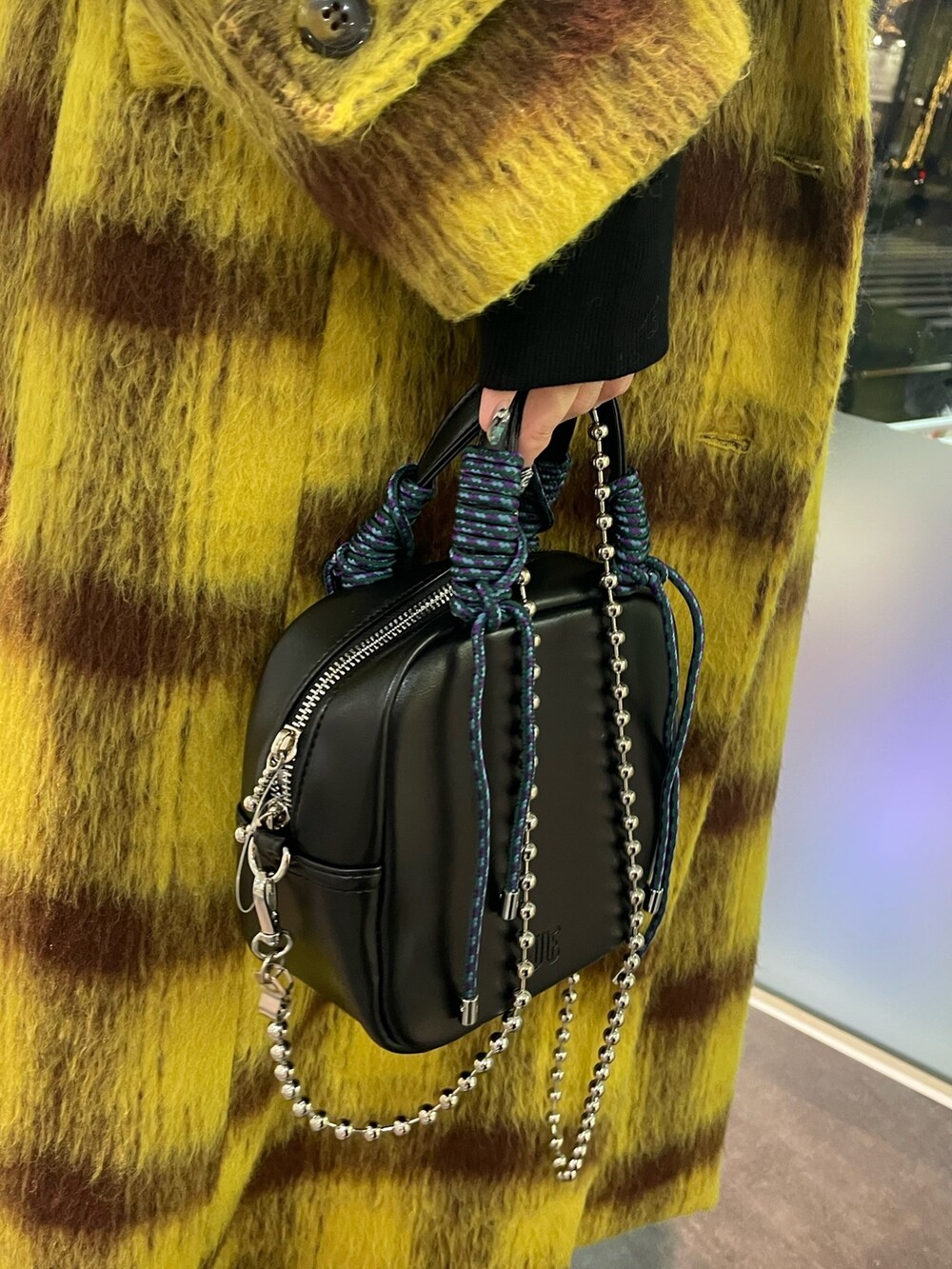 イエロー系のチェスターコート、ブラック系のパーカー、ブラック系のショルダーバッグを着用したレディースの冬コーディネートの9枚目の写真