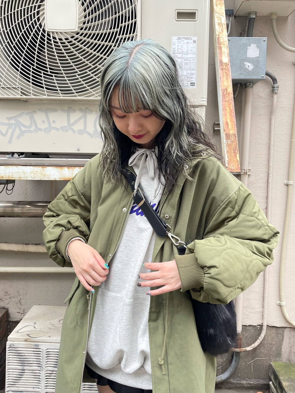 グリーン系のモッズコート、ブラック系のスカート、ブラック系のブーツを着用したレディースの秋コーディネートの4枚目の写真