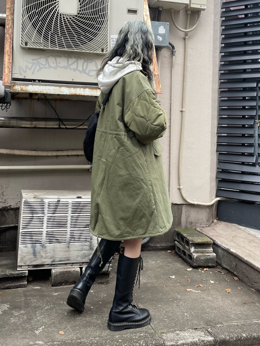 グリーン系のモッズコート、ブラック系のスカート、ブラック系のブーツを着用したレディースの秋コーディネートの3枚目の写真