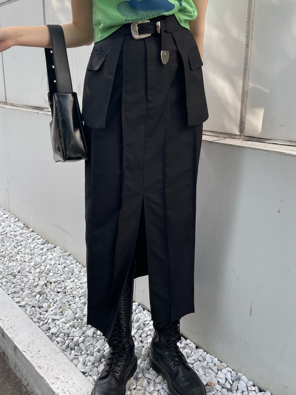 グリーン系のTシャツ/カットソー、ブラック系のスカート、ブラック系のブーツを着用したレディースの春コーディネートの6枚目の写真