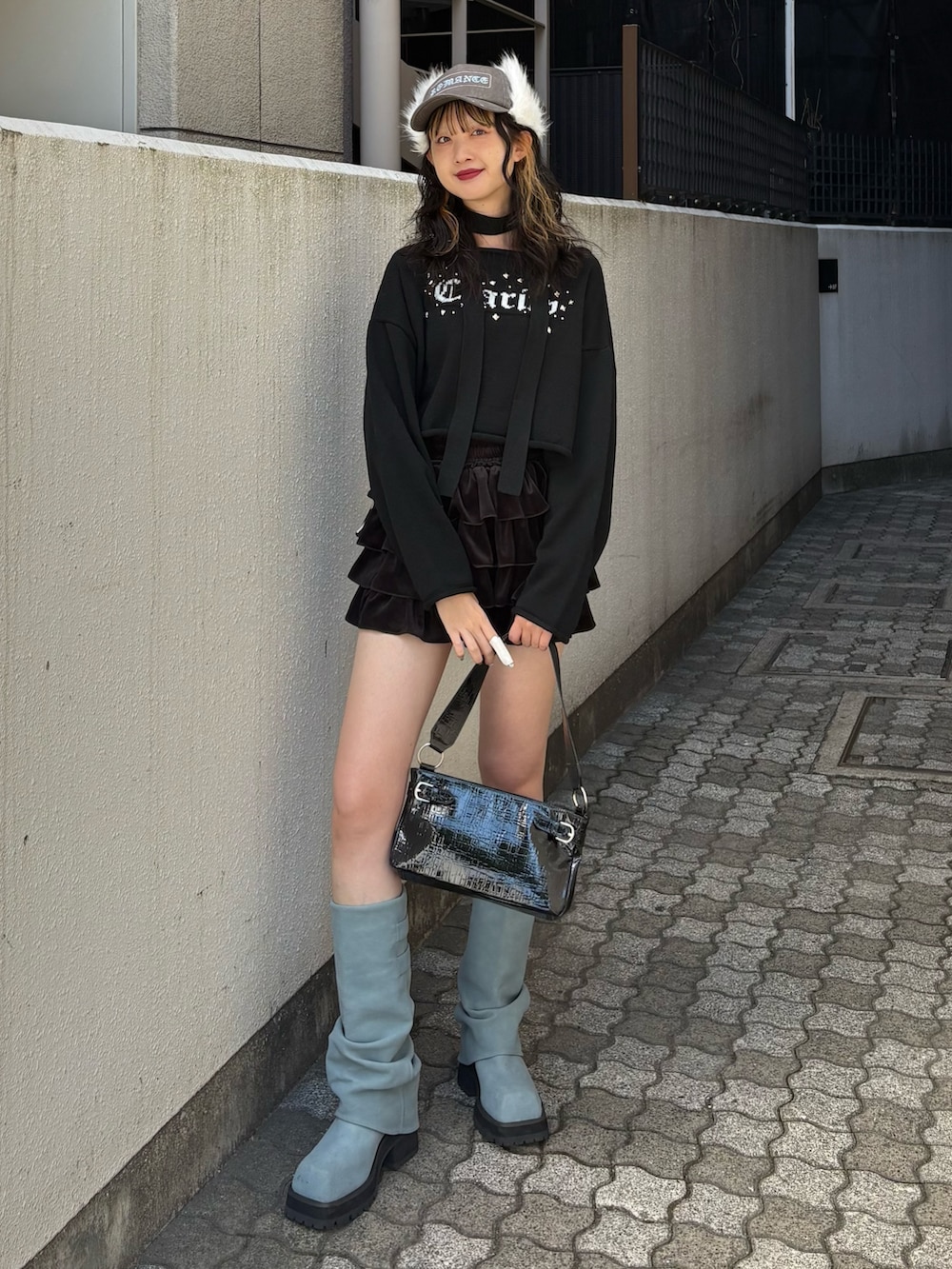 ブラック系のニット/セーター、ブラック系のスカート、ブルー系のブーツを着用したレディースの秋コーディネートの2枚目の写真