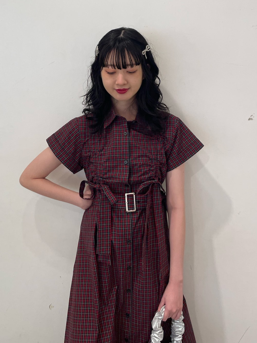 レッド系のワンピース、シルバー系のハンドバッグ、ブラック系のブーツを着用したレディースの春コーディネートの5枚目の写真