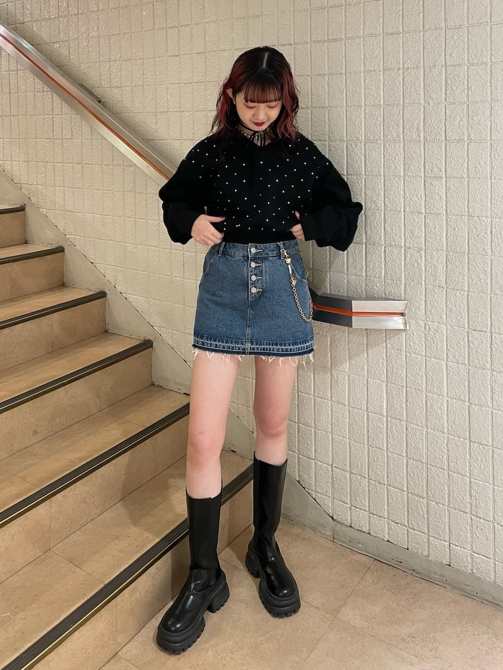 ブラック系のスウェット、ブルー系のデニムパンツ、ブラック系のブーツを着用したレディースの冬コーディネートの2枚目の写真
