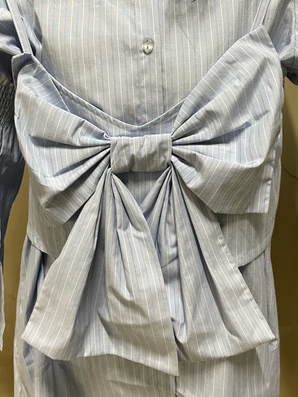 ブルー系のシャツワンピース、ゴールド系のハンドバッグ、ブラック系のブーツを着用したレディースの夏コーディネートの6枚目の写真