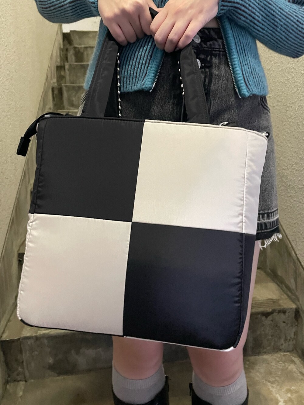 ブルー系のニット/セーター、ブラック系のデニムパンツ、ホワイト系のトートバッグを着用したレディースの秋コーディネートの7枚目の写真