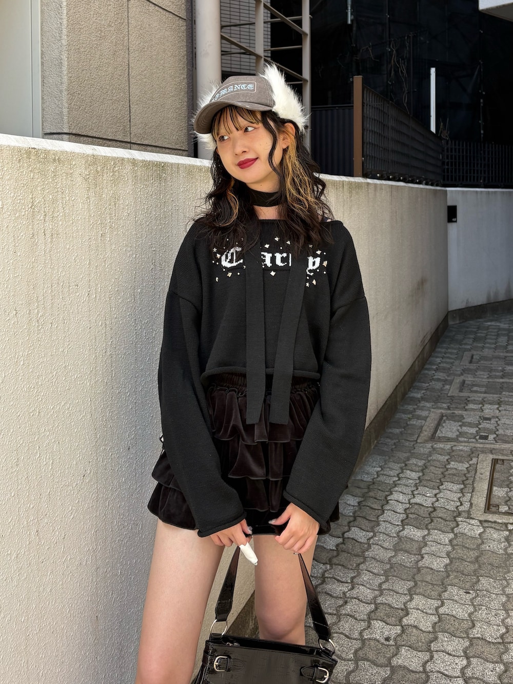 ブラック系のニット/セーター、ブラック系のスカート、ブルー系のブーツを着用したレディースの秋コーディネートの4枚目の写真