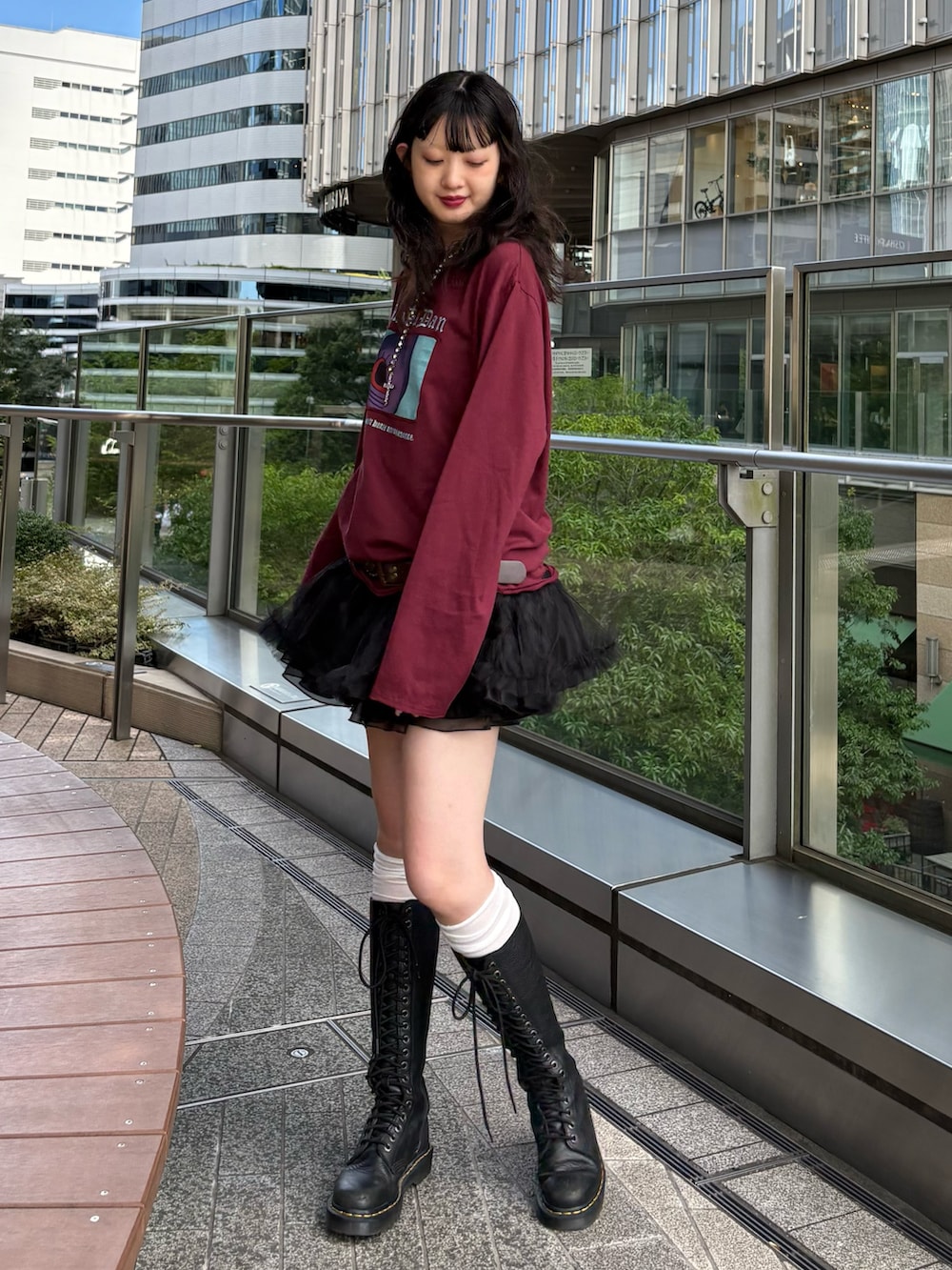 レッド系のTシャツ/カットソー、ブラック系のスカート、ブラック系のブーツを着用したレディースの夏コーディネートの3枚目の写真