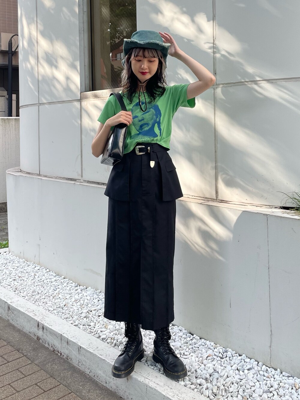 グリーン系のTシャツ/カットソー、ブラック系のスカート、ブラック系のブーツを着用したレディースの春コーディネートの2枚目の写真