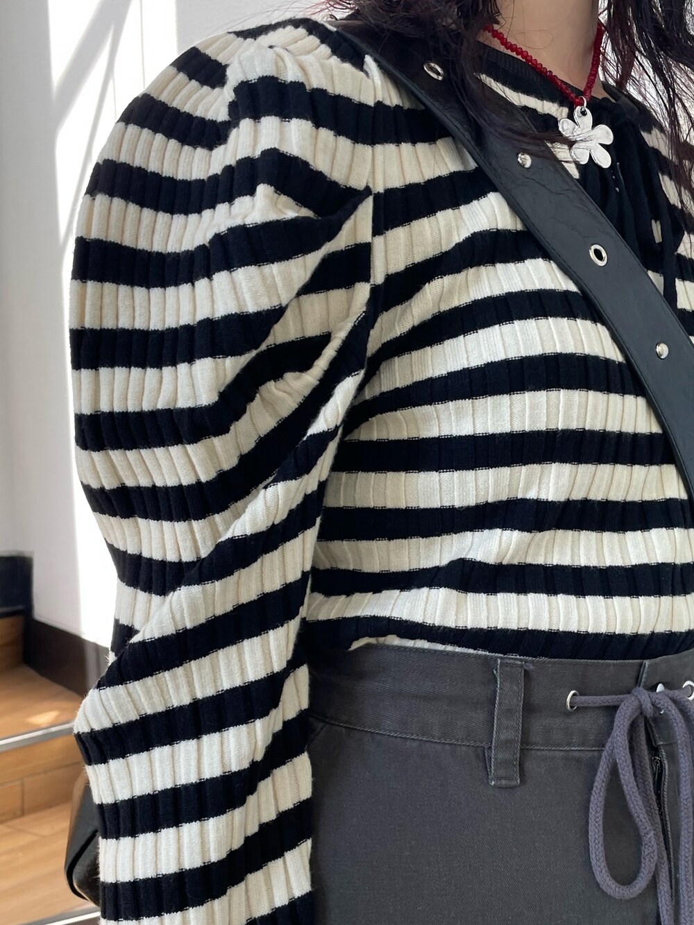 ホワイト系のニット/セーター、ブラック系のブーツ、ブラック系のスカートを着用したレディースの冬コーディネートの6枚目の写真