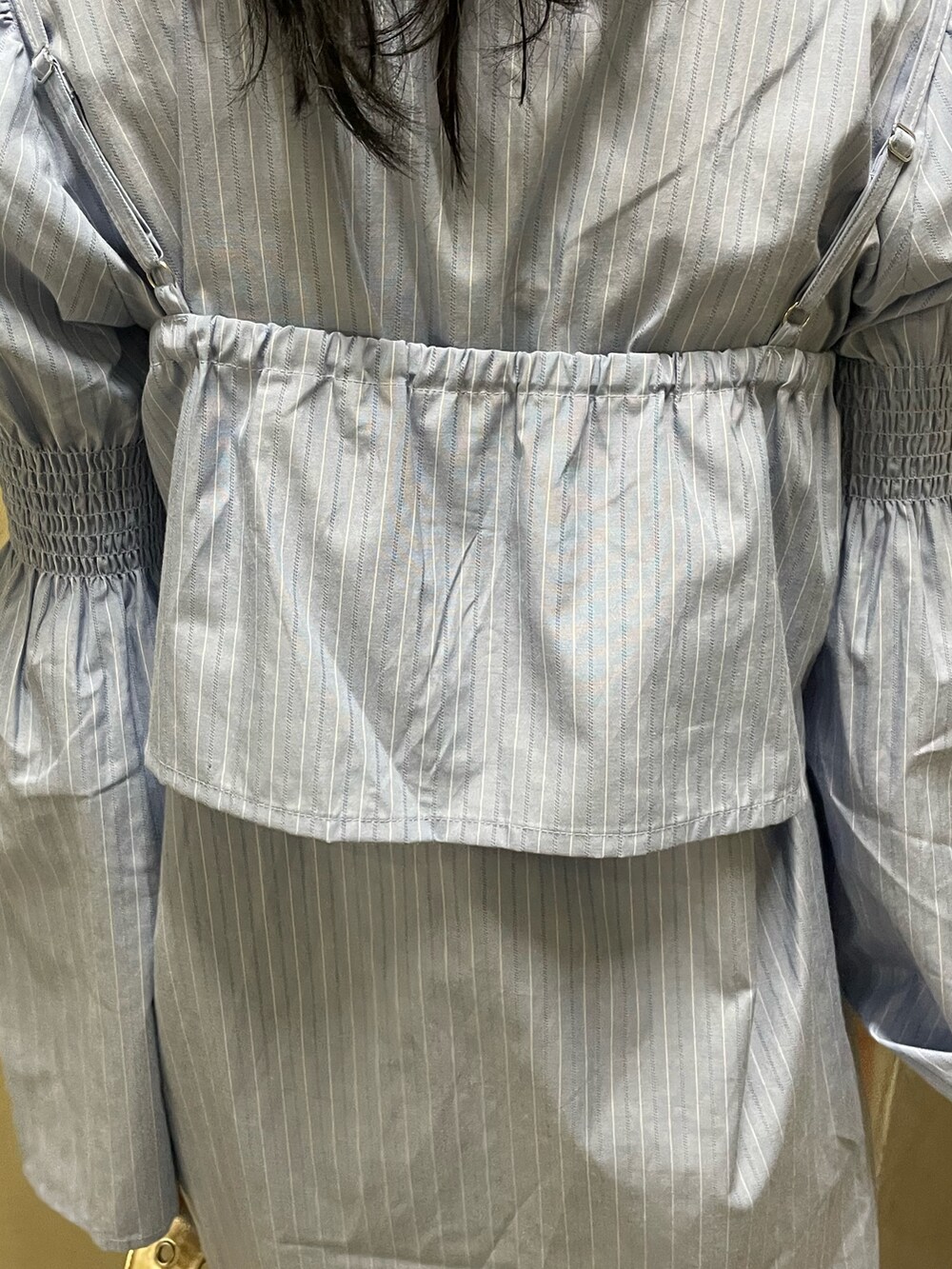 ブルー系のシャツワンピース、ゴールド系のハンドバッグ、ブラック系のブーツを着用したレディースの夏コーディネートの8枚目の写真