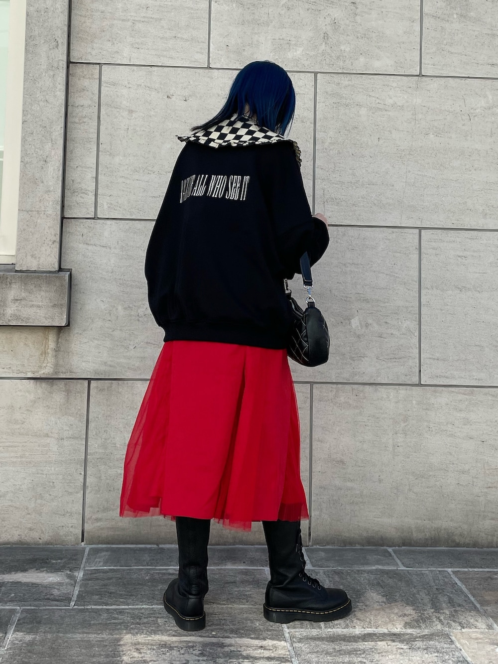 ブラック系のスウェット、レッド系のジャンパースカート、ブラック系のブーツを着用したレディースの冬コーディネートの3枚目の写真