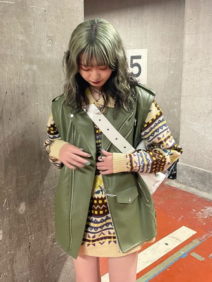 ブラック系のブーツ、ホワイト系のハンドバッグ、グリーン系のライダースジャケットを着用したレディースの秋コーディネートの5枚目の写真