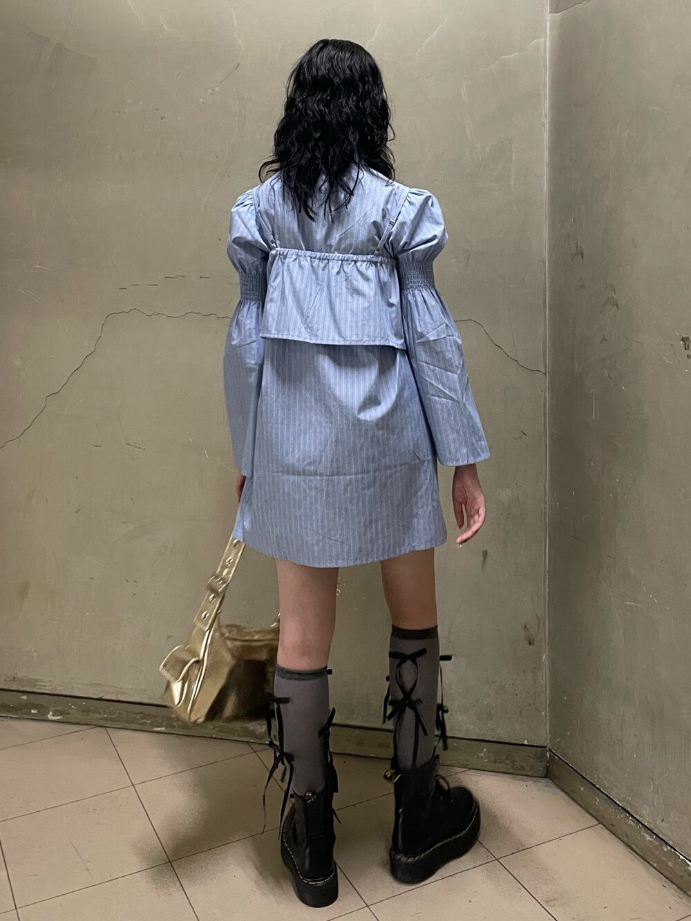 ブルー系のシャツワンピース、ゴールド系のハンドバッグ、ブラック系のブーツを着用したレディースの夏コーディネートの4枚目の写真