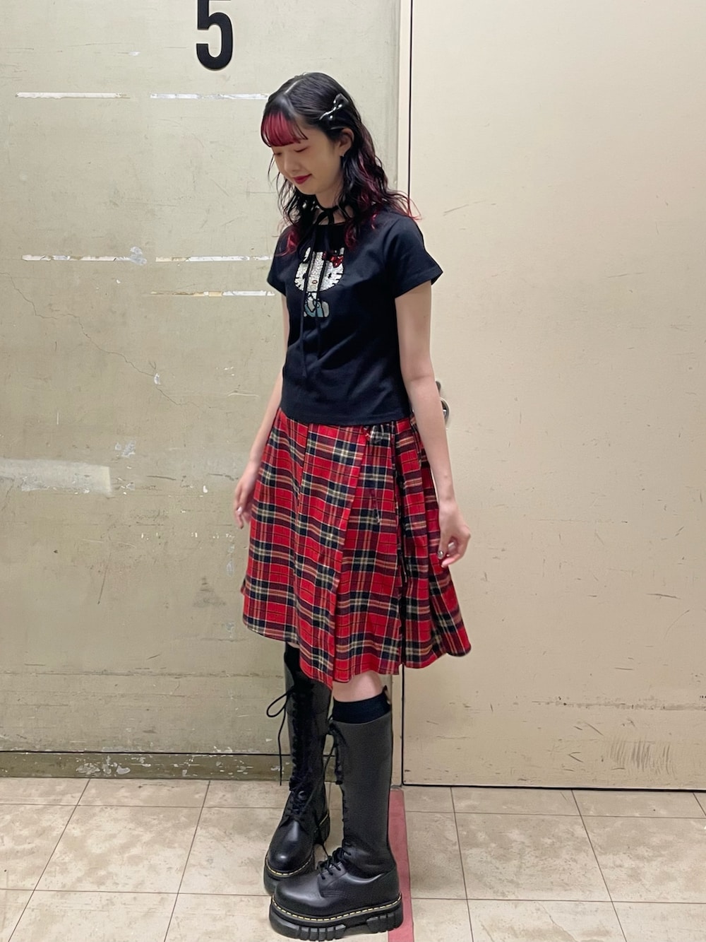 ブラック系のTシャツ/カットソー、レッド系のスカート、ブラック系のブーツを着用したレディースの春コーディネートの3枚目の写真