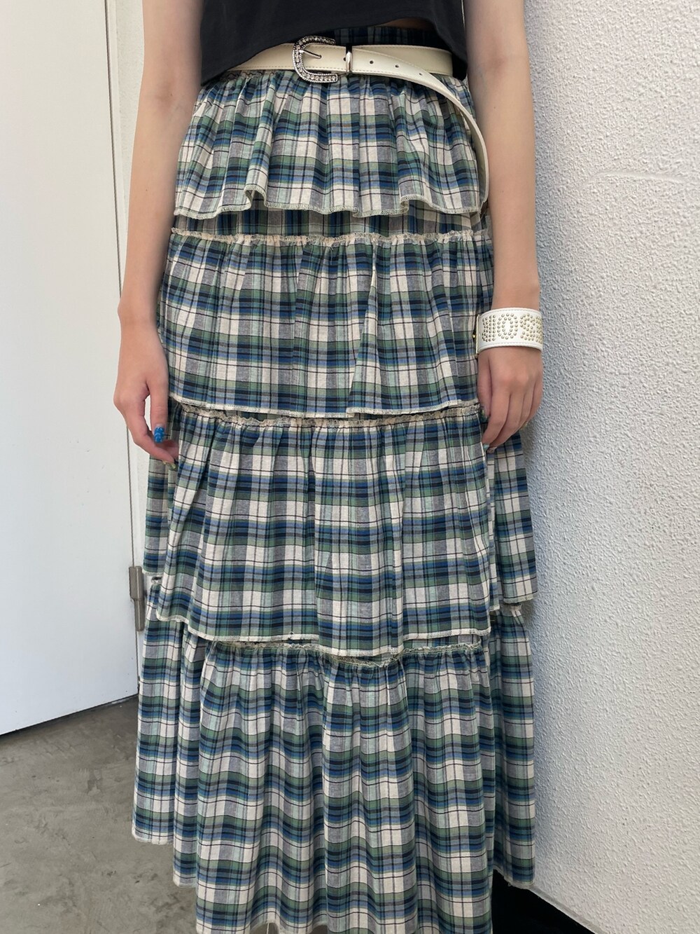 グリーン系のスカート、ブラック系のTシャツ/カットソー、ホワイト系のサンダルを着用したレディースの夏コーディネートの5枚目の写真