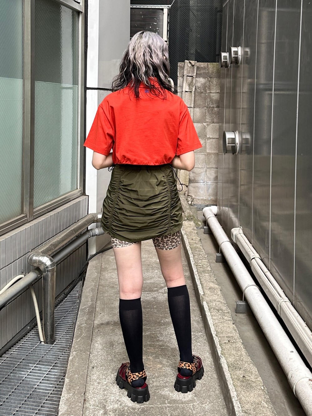 レッド系のTシャツ/カットソー、グリーン系のスカート、ベージュ系のその他パンツを着用したレディースの春コーディネートの3枚目の写真