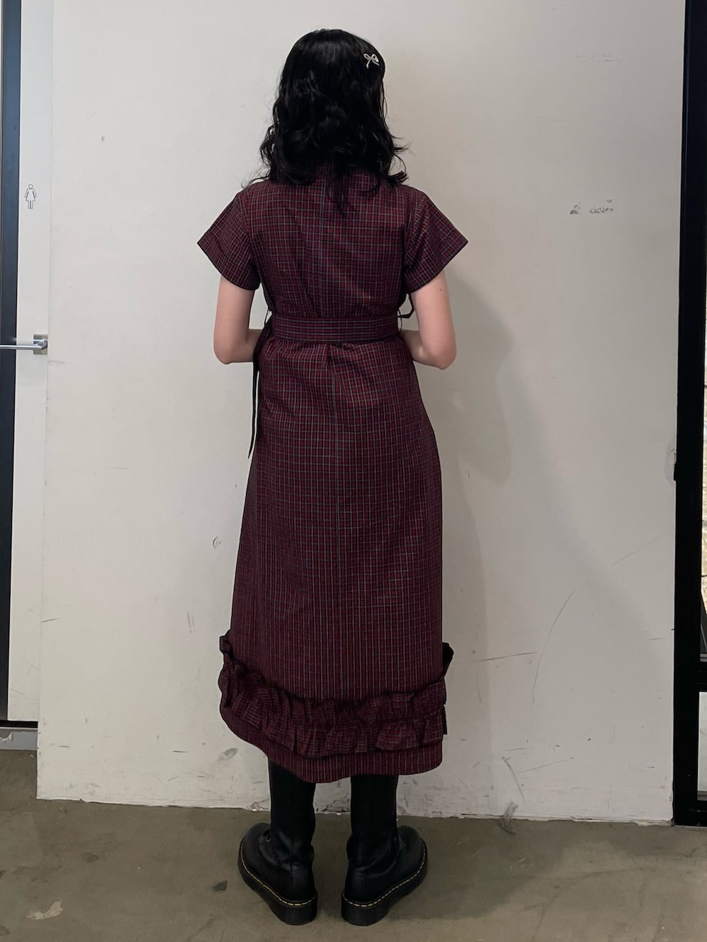 レッド系のワンピース、シルバー系のハンドバッグ、ブラック系のブーツを着用したレディースの春コーディネートの3枚目の写真