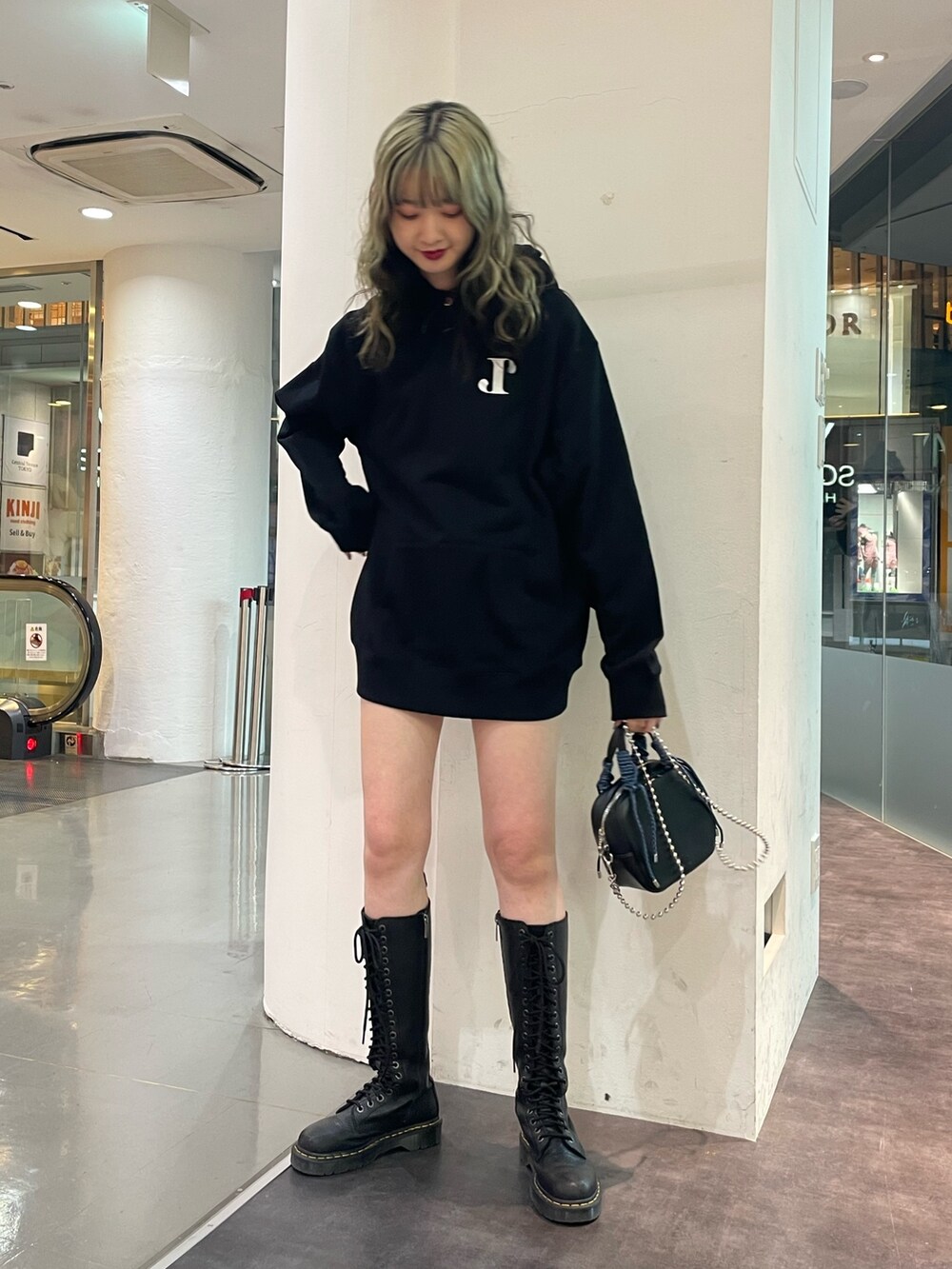 イエロー系のチェスターコート、ブラック系のパーカー、ブラック系のショルダーバッグを着用したレディースの冬コーディネートの5枚目の写真