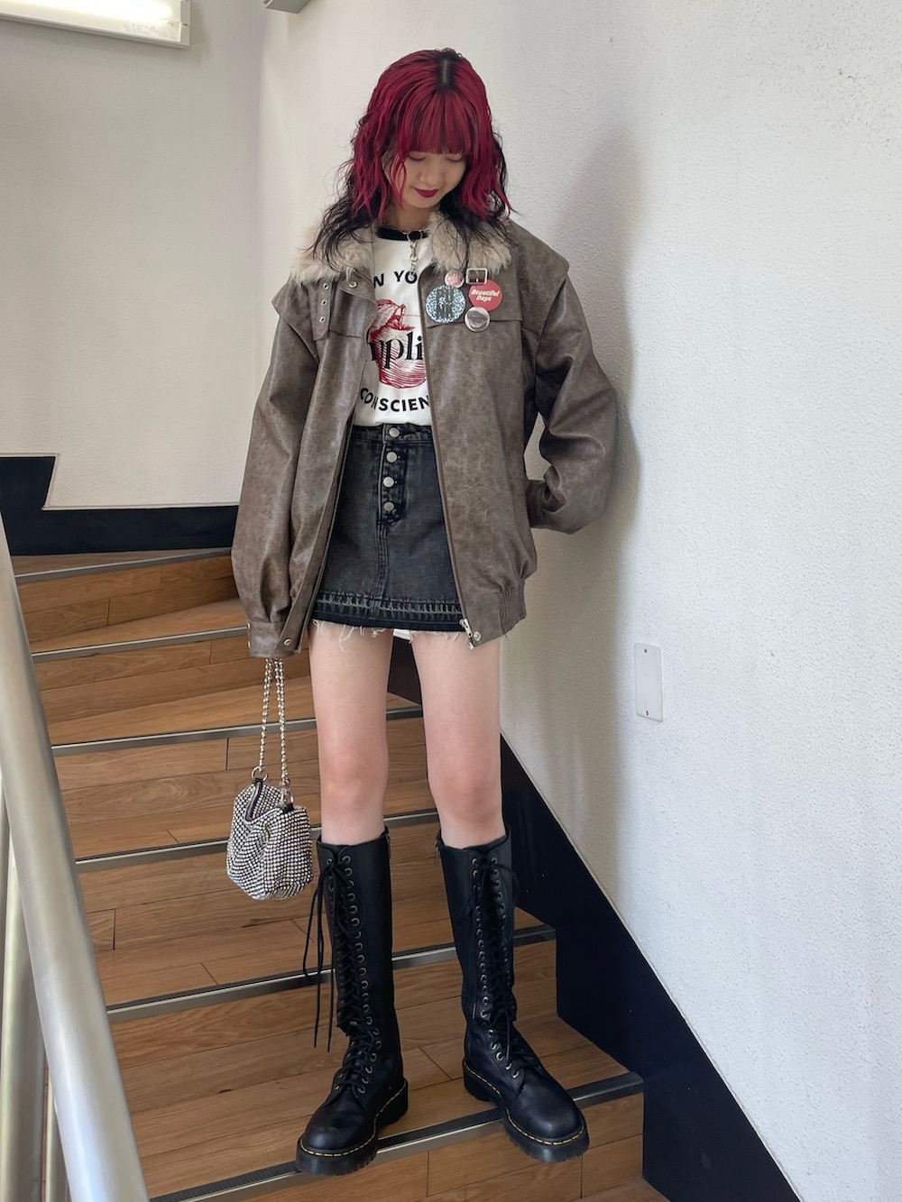 ブラック系のデニムパンツ、ブラウン系のブルゾン、ホワイト系のTシャツ/カットソーを着用したレディースの秋コーディネートの2枚目の写真