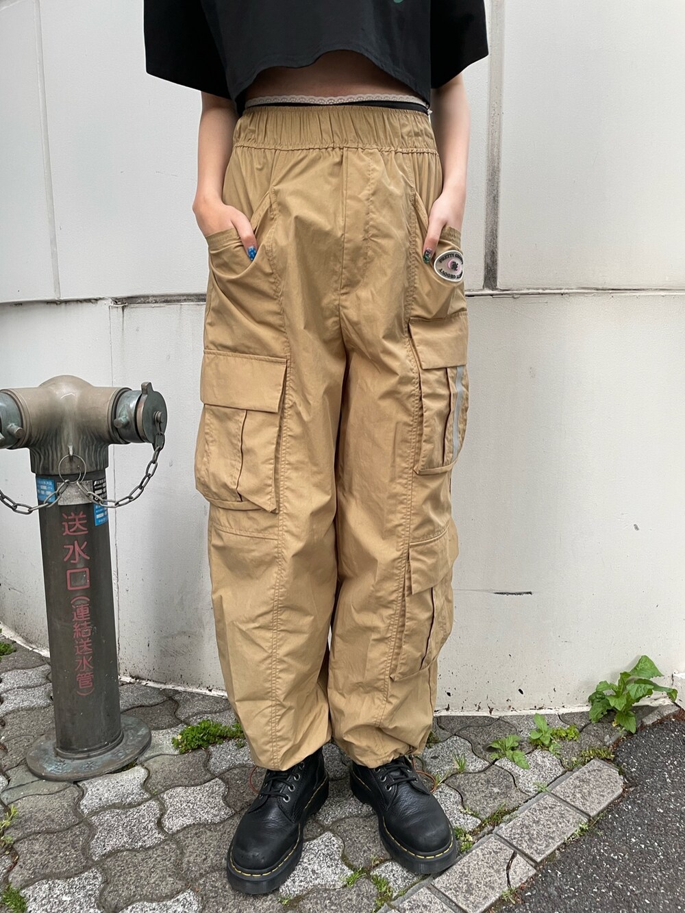 ベージュ系のカーゴパンツ、ブラック系のTシャツ/カットソー、ブラック系のブーツを着用したレディースの夏コーディネートの8枚目の写真