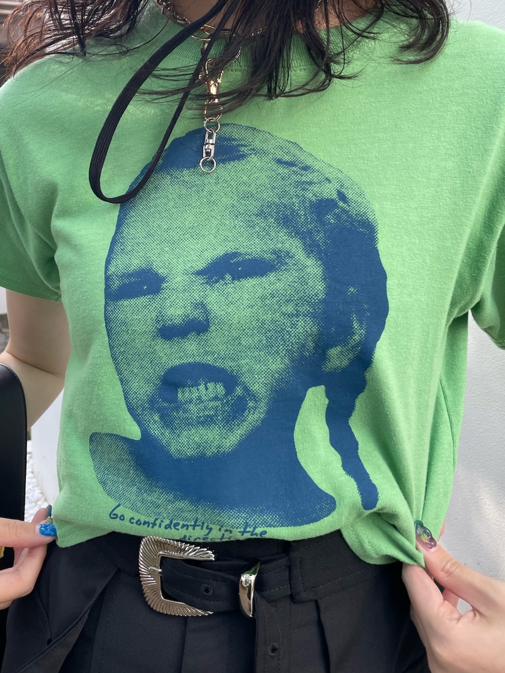 グリーン系のTシャツ/カットソー、ブラック系のスカート、ブラック系のブーツを着用したレディースの春コーディネートの5枚目の写真