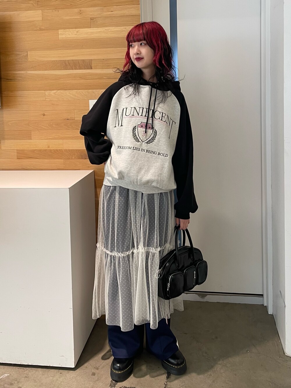 グレー系のパーカー、ホワイト系のワンピース、ブラック系のボストンバッグを着用したレディースの冬コーディネートの2枚目の写真