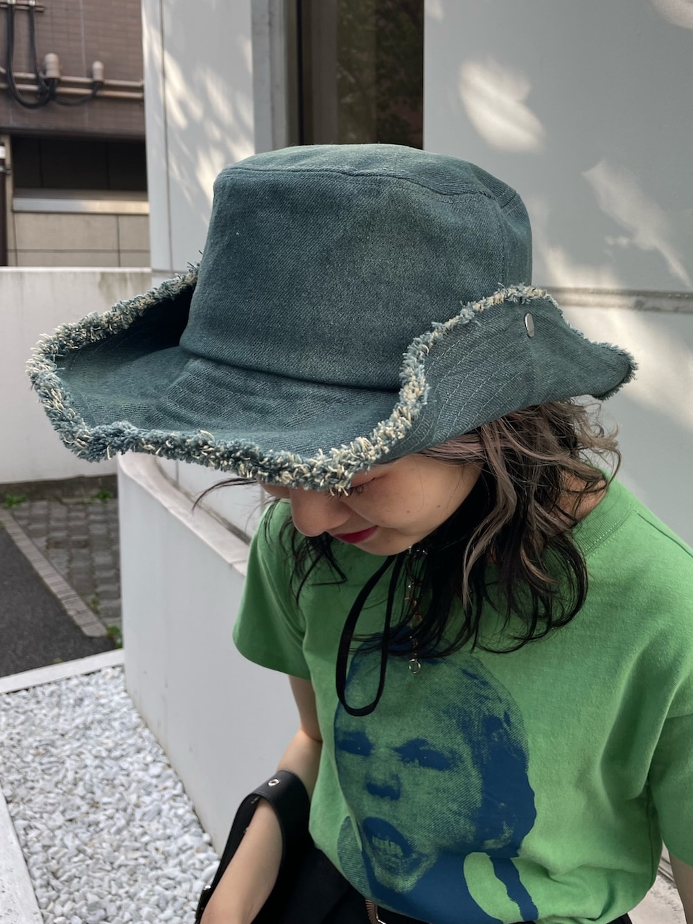 グリーン系のTシャツ/カットソー、ブラック系のスカート、ブラック系のブーツを着用したレディースの春コーディネートの8枚目の写真