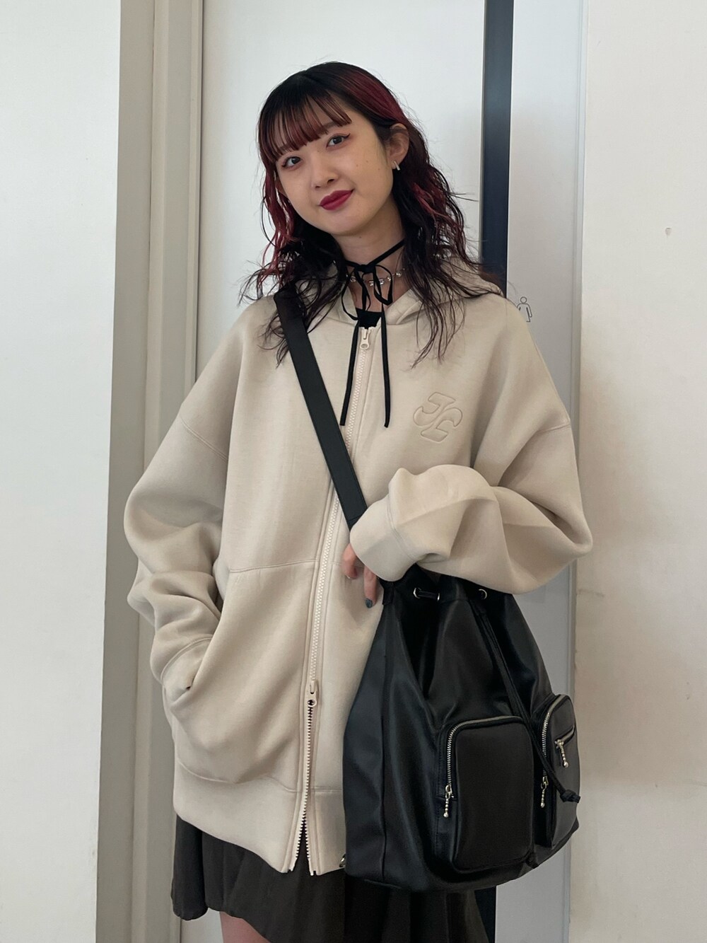 ホワイト系のパーカー、ブラック系のバックパック/リュック、ブラック系のスカートを着用したレディースの冬コーディネートの4枚目の写真