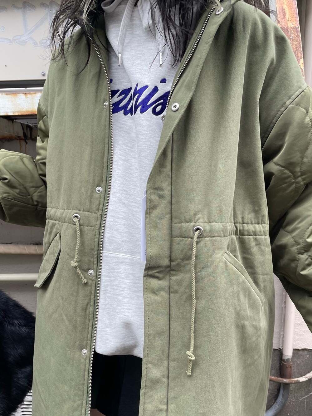 グリーン系のモッズコート、ブラック系のスカート、ブラック系のブーツを着用したレディースの秋コーディネートの5枚目の写真