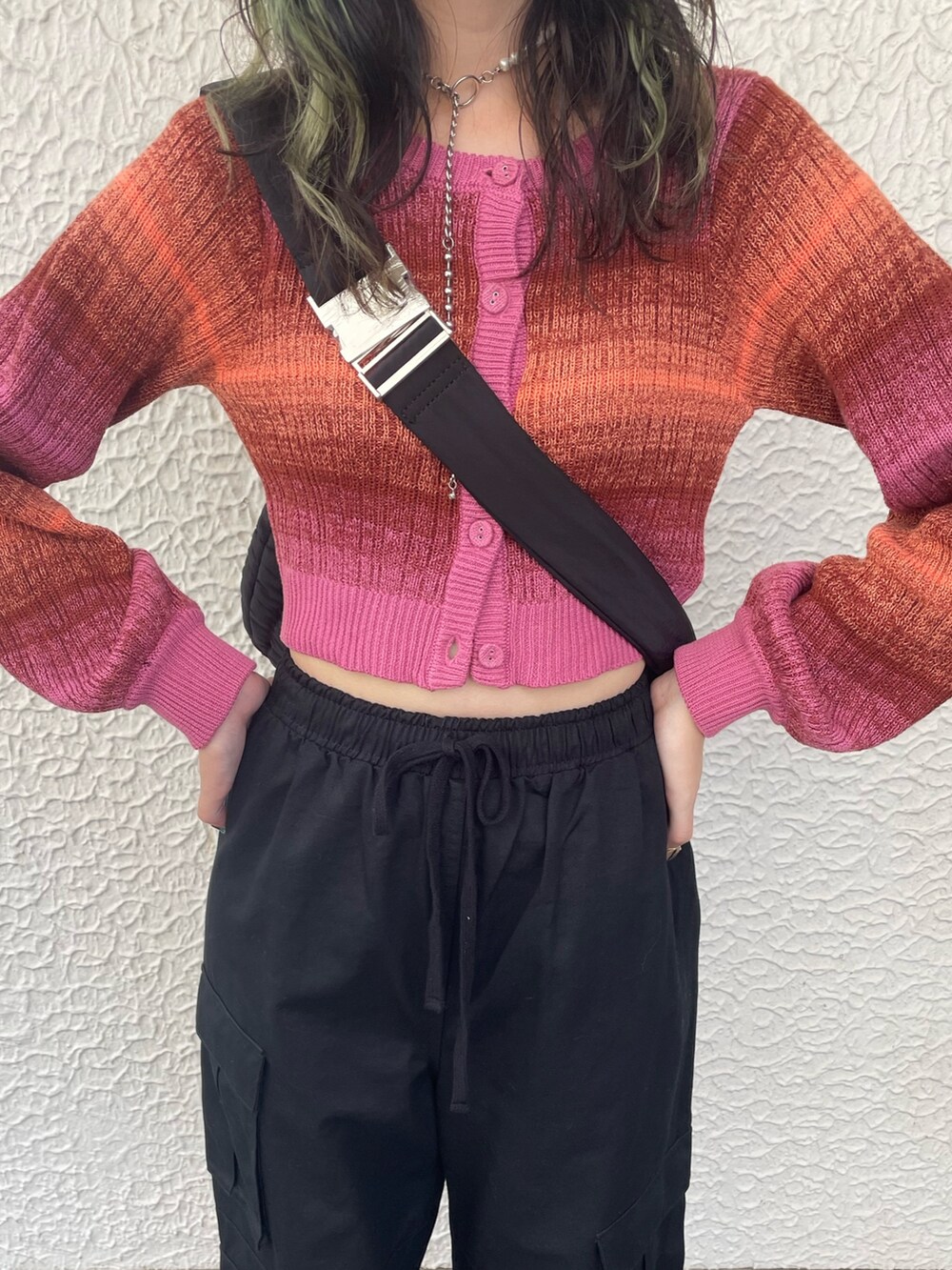 ブラック系のカーゴパンツ、ブラック系のハンドバッグ、ピンク系のカーディガン/ボレロを着用したレディースの秋コーディネートの4枚目の写真