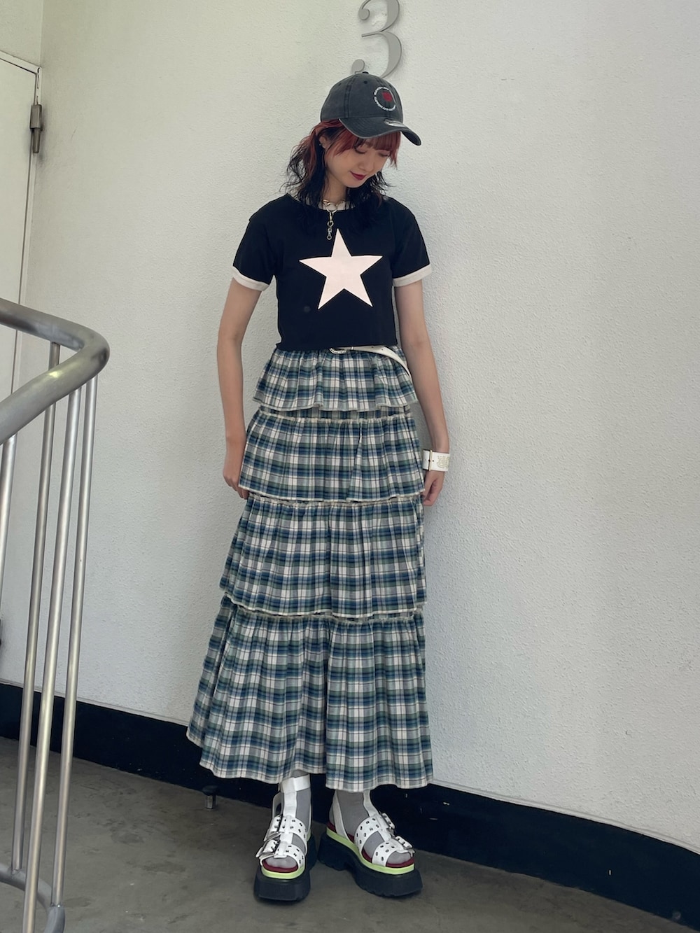 グリーン系のスカート、ブラック系のTシャツ/カットソー、ホワイト系のサンダルを着用したレディースの夏コーディネートの2枚目の写真