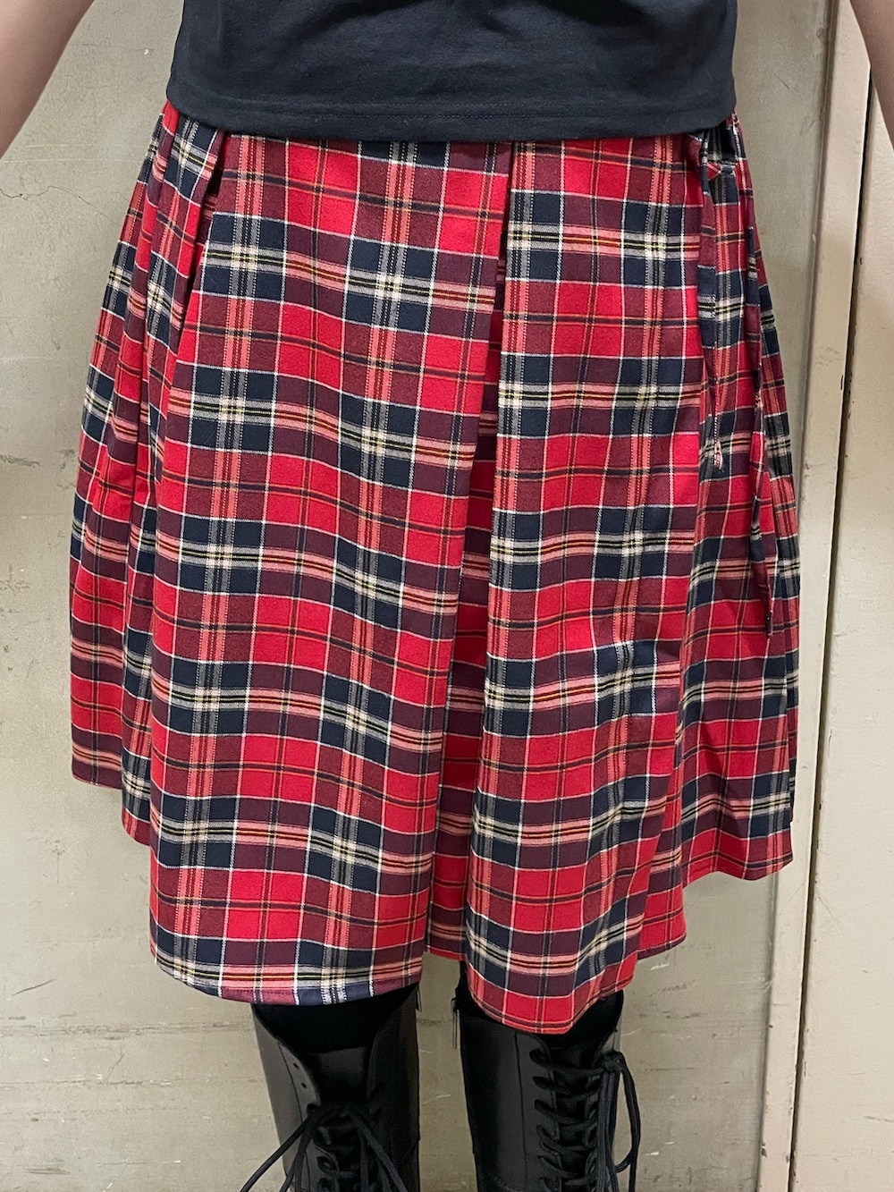 ブラック系のTシャツ/カットソー、レッド系のスカート、ブラック系のブーツを着用したレディースの春コーディネートの8枚目の写真