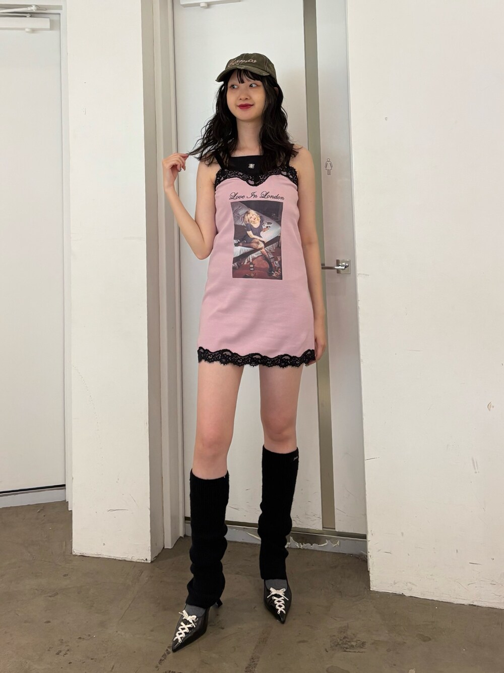 ピンク系のワンピース、ブラック系のパンプス、グリーン系のキャップを着用したレディースの夏コーディネートの2枚目の写真