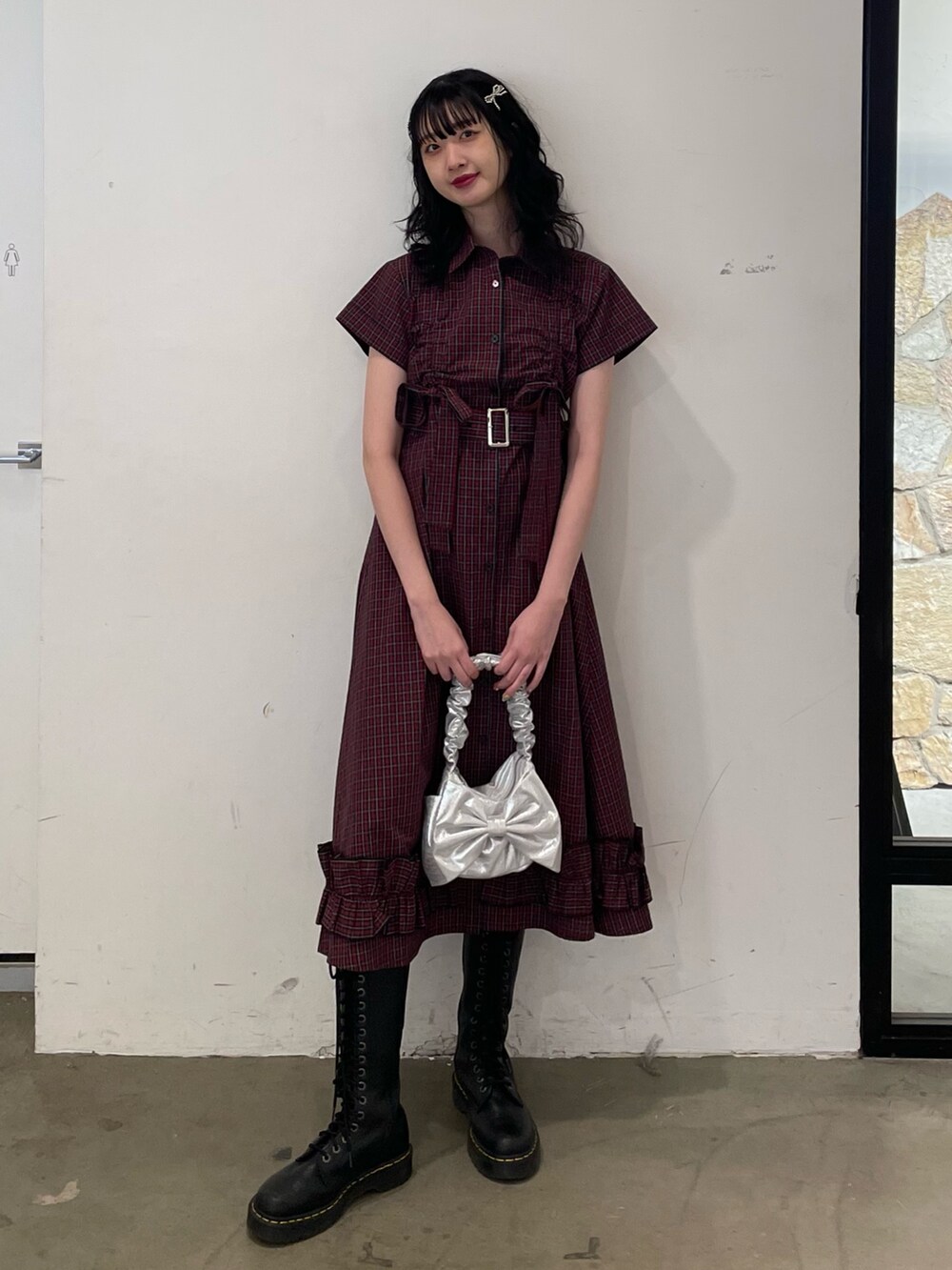 レッド系のワンピース、シルバー系のハンドバッグ、ブラック系のブーツを着用したレディースの春コーディネートの2枚目の写真