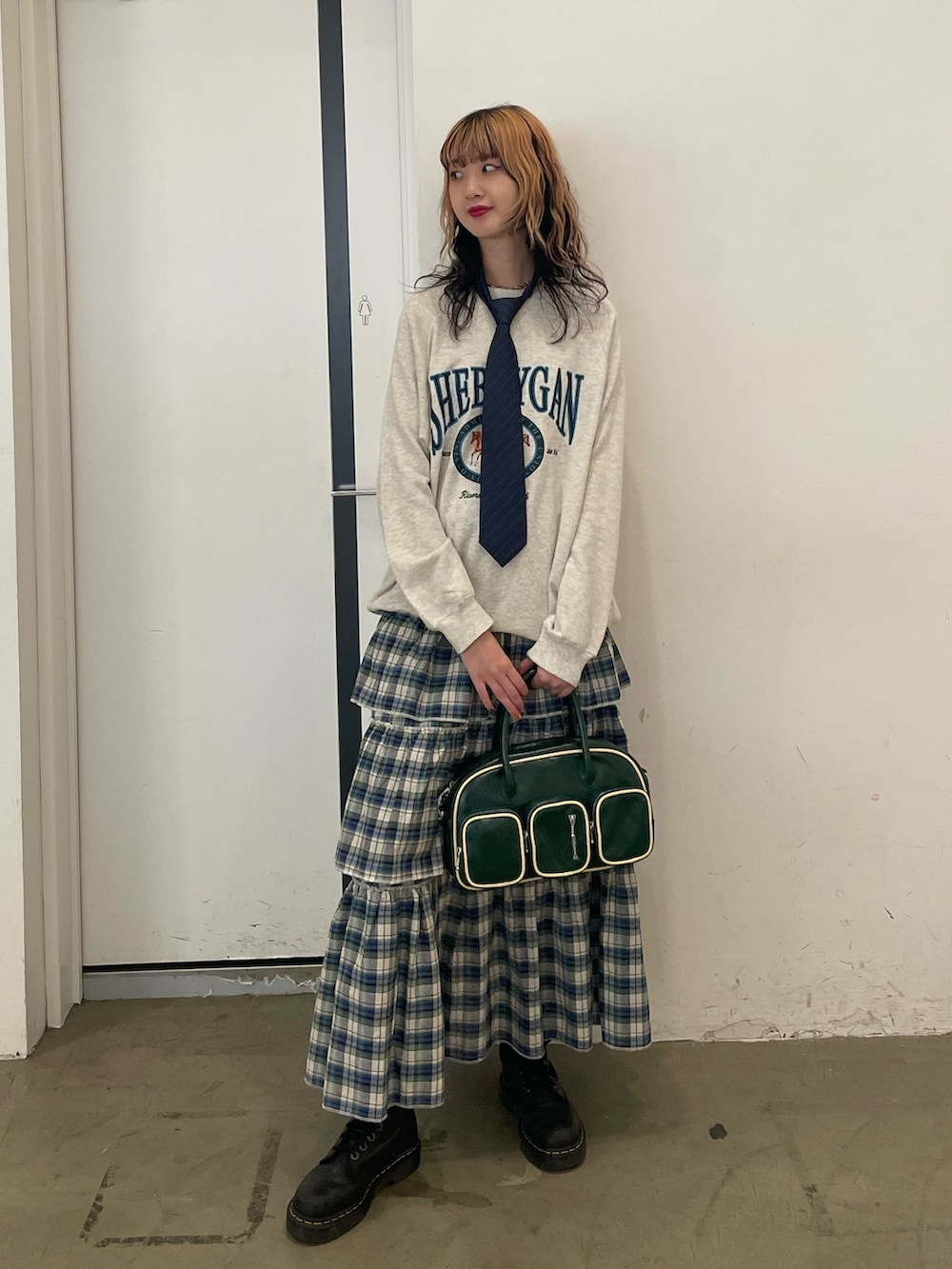 グレー系のスウェット、グリーン系のスカート、グリーン系のボストンバッグを着用したレディースの夏コーディネートの2枚目の写真